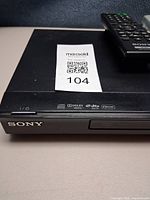 Front left corner of Sony DVD player with logo, format icons and remote on top