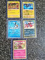 Front view of all five sleeved holographic Pokémon cards