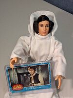Princess Leia doll holding blue Star Wars trading card featuring Han Solo