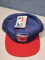 Front view showing crown, red brim, embroidered Nets logo