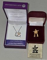 Overall view of pendant in Woods box and Inukshuk brooch in velvet box with pamphlet