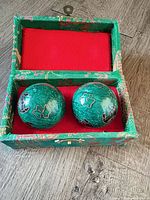 Open storage box showing two green enamel Baoding balls in red lining