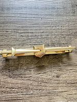 Front view of gold-tone Hadley tie clip on wood surface