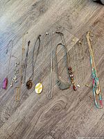 All ten necklaces laid flat on floor showcasing full lengths and pendants
