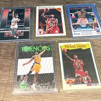 Five sleeved sports cards laid out on a wooden surface