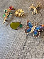 overview of five brooches and pins on wood surface
