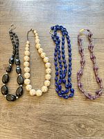 All four bead necklaces laid flat on wood surface