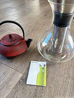 Teapot, carafe with infuser inserted, and booklet on floor