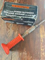 Tool and box overview showing full driver with orange grip beside original black Remington box