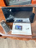 Front view of RimooDy 7" touchscreen head unit with remote and manual