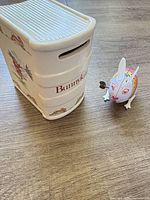 Ceramic Bunnykins coin bank and tin wind-up bunny toy on wood surface