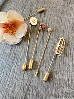 All five stick pins laid on wood surface showing heads and clutches