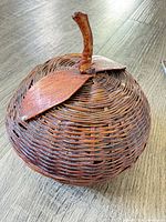 Front view of apple-shaped wicker basket with lid in place