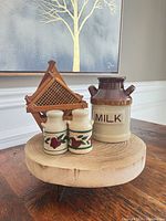 Front view of milk canister, two floral jars, stacked bamboo coasters
