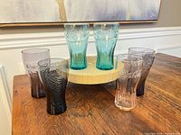 Front view of six tinted Coca-Cola glasses on stand