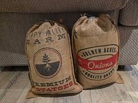 Front view of both burlap sacks standing upright displaying printed graphics