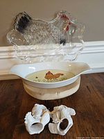 Overall lot showing glass hen platter on top, ceramic hen dish below, four hen napkin rings in front