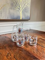 Set showing pitcher and four glasses on wooden table