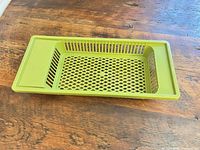 Angled top view of green plastic drainer basket on wooden surface