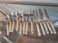 Full 18-piece flatware set arranged on glass surface