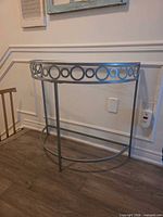 Front view of demi-lune console table showing circular motif and glass top