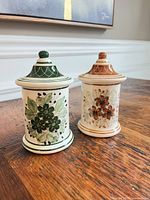 Both ceramic jars front view showing floral designs and lids