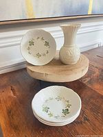 Group view of three bowls stacked and one bowl standing with vase on wood stand