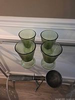four green textured glass goblets and metal ice cream scoop overview