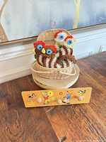 Four crocheted chicken coasters in wicker basket with wall hanger