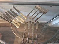 Overview of all 13 flatware pieces on glass table