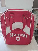 Front view of red and white Spalding vinyl bowling tote with handles