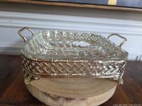 Square glass dish seated in gold-tone lattice holder, angled side view