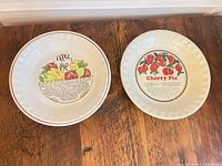 Top view of both ceramic pie plates, Apple Pie and Cherry Pie designs visible