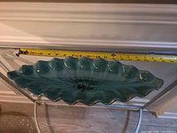 Top view showing oval ruffled bowl and measuring tape indicating length