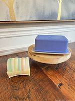 Butter dish with purple lid on off-white base beside stack of pastel lids