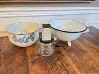 Overall view of enamel mixing bowl, colander and glass hand grinder