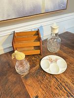 Full lot showing wood rack, glass syrup dispenser, cut glass bottle, ceramic spoon rest