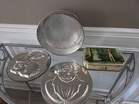 Overall lot: three metal cake molds and decorative tin box on table