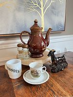 All items grouped on table showing teapot, glass deer, milk glass mug, shakers, cup and saucer