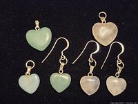 Six heart gemstones and two sterling hooks arranged on black background