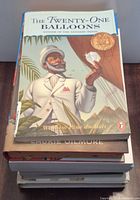 Stack of books showing front cover of The Twenty-One Balloons and edges of others