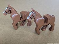 Front left three-quarter view of both brown LEGO horses standing
