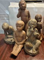 Front view of all five boy sculptures displaying poses and bronze finish