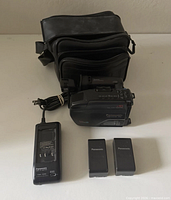 Entire bundle showing camcorder, charger with cord, two batteries, Ryka bag