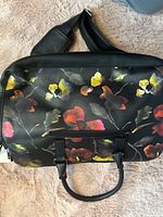 Front view showing floral panel, handles, shoulder strap, front zip pocket