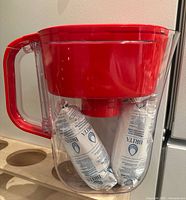 Side view of red Brita pitcher showing two sealed filters inside reservoir