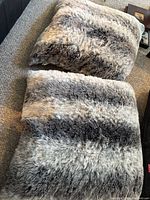 Two large shaggy faux-fur floor pillows on carpet