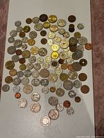 Overall spread of approximately 80 world coins on tabletop