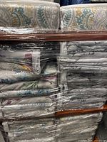 Stacked unopened duvet covers on shelf, assorted patterns visible