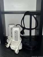 Two white tower power strips and black base power strip with headphone stand